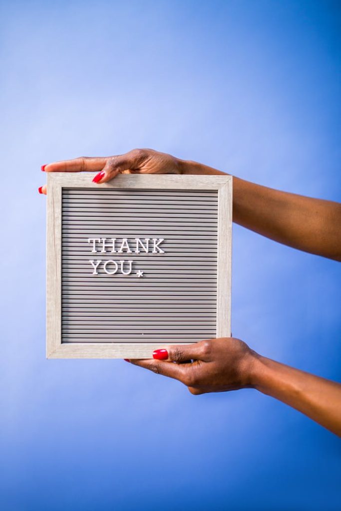 person-holding-a-board-with-a-text-saying-thank-you-7564251 Hands holding thank you sign on blue backdrop, perfect for social media and digital marketing.